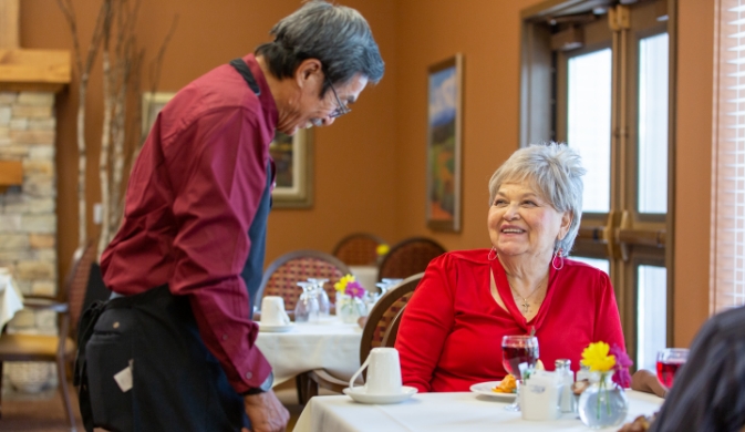 senior resident at a dining table with a waiter