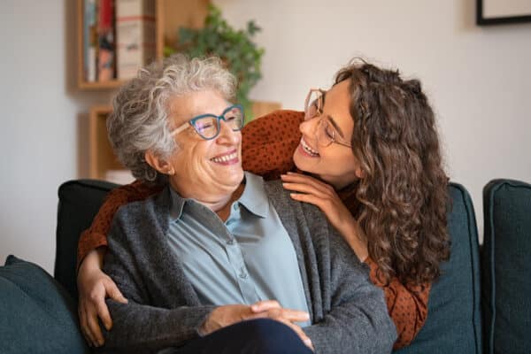 Grandmother and granddaughter laughing and embracing at home