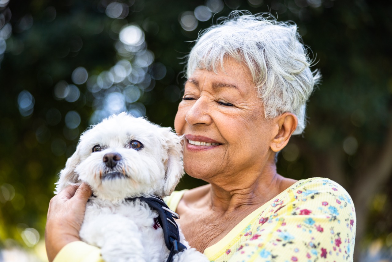 A mixed race senior woman holding her puppy outdoors